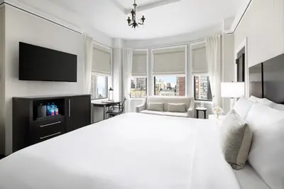a white bedroom with a large bed and a tv at The Gregorian New York City in New York