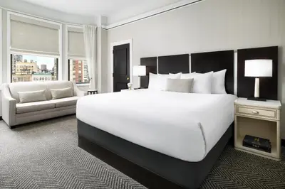 a bedroom with a large white bed and a couch at The Gregorian New York City in New York