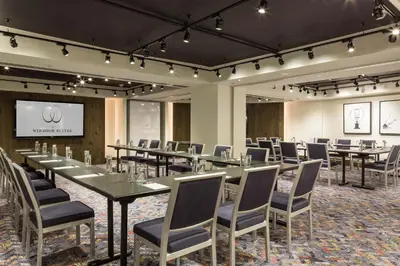 a conference room with tables and chairs and a screen at The Windsor Suites in Philadelphia