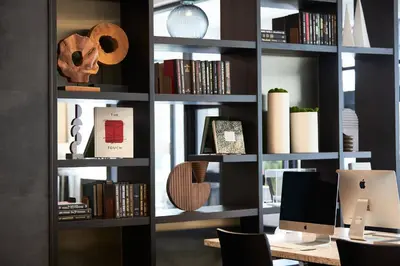 a book shelf with books and a computer on it at AC Hotel by Marriott Bridgewater in Bridgewater