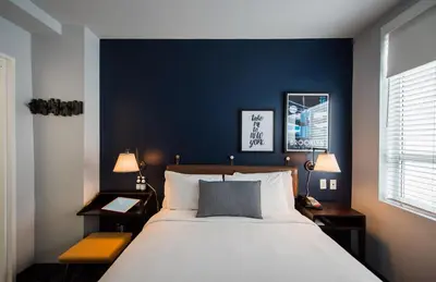 a bedroom with a large bed and a blue wall at U Hotel Fifth Avenue, Empire State Building in New York