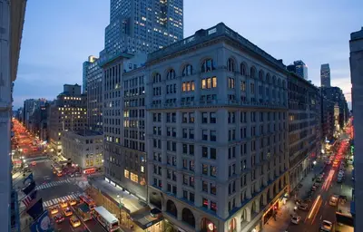 a large white building on a city street at night at U Hotel Fifth Avenue, Empire State Building in New York