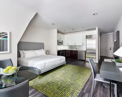 a bedroom with a bed and a table and a kitchen at AKA Times Square in New York