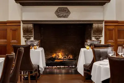 a fireplace in the dining room of a restaurant with tables and chairs at The Chemists Club Hotel in New York