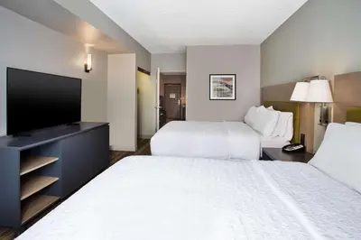 a hotel room with two beds and a flat screen tv at Hampton Inn & Suites By Hilton- Newark Airport Elizabeth in Newark