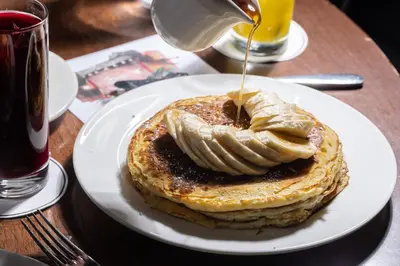 a plate of pancakes with syrup on a table at Roxy Hotel New York in New York