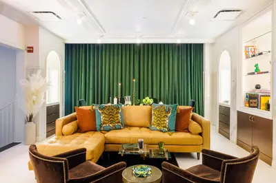 a living room with a couch and a green curtain at Roxy Hotel New York in New York