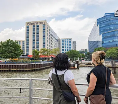 two women standing by a fence looking at a river at Sheraton Lincoln Harbor Hotel in Weehawken
