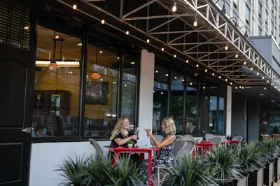 two women sitting at tables outside of a building at Sheraton Lincoln Harbor Hotel in Weehawken