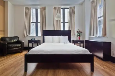 a bedroom with a bed and a chair and windows at Eurostars Wall Street in New York