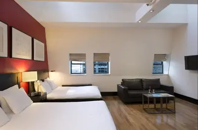 a hotel room with two beds and a couch at Eurostars Wall Street in New York