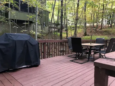a wooden deck with a table and chairs on it at Cozy Cottage at Saw Creek in Bushkill