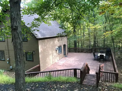 a large wooden deck in front of a house at Cozy Cottage at Saw Creek in Bushkill
