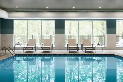 a pool in a hotel with chairs and windows at Holiday Inn Express & Suites - Middletown - Goshen by IHG in Middletown