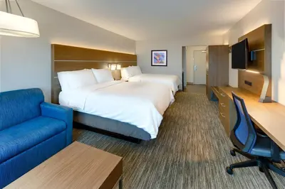 a hotel room with a large bed and a blue couch at Holiday Inn Express & Suites - Middletown - Goshen by IHG in Middletown
