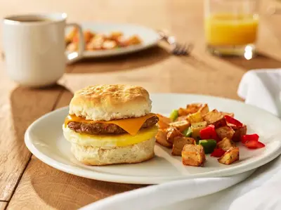 a plate of food with a breakfast sandwich and vegetables at Four Points by Sheraton Philadelphia Airport in Philadelphia