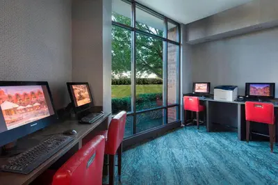 an office with two computers and red chairs and a window at Sheraton Suites Philadelphia Airport in Philadelphia