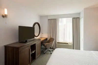 a hotel room with a bed and a desk with a television at Hampton Inn Manhattan Chelsea in New York