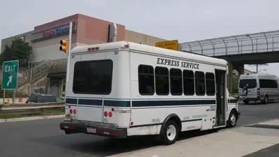 a white bus is driving down the street at Super 8 by Wyndham North Bergen NJ/NYC Area in North Bergen