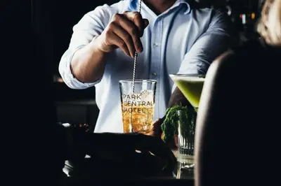 a man sitting at a table with a drink at Park Central Hotel New York in New York