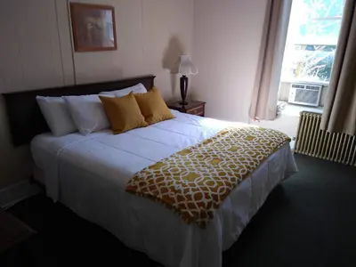 a bedroom with a large bed with yellow pillows and a window at Hotel Wayne in Honesdale