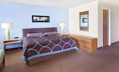 a bedroom with a bed and a table and a mirror at Super 8 by Wyndham Newburgh/West Point Stewart Intl Airport in Newburgh