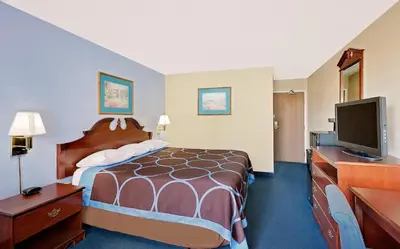 a hotel room with a bed and a flat screen tv at Super 8 by Wyndham Newburgh/West Point Stewart Intl Airport in Newburgh
