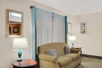 a living room with a chair and a window at Super 8 by Wyndham Newburgh/West Point Stewart Intl Airport in Newburgh