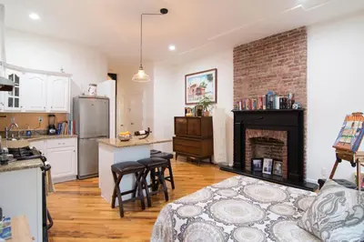 a kitchen and a living room with a fireplace at Historic 1869 Brownstone 15 min to NYC downtown in Jersey City