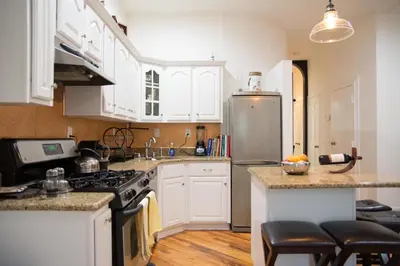a kitchen with white cabinets and a stainless steel refrigerator at Historic 1869 Brownstone 15 min to NYC downtown in Jersey City