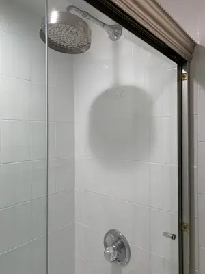 a shower with a glass door and a shower head at Historic 1869 Brownstone 15 min to NYC downtown in Jersey City