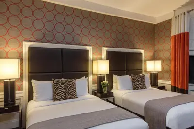two beds in a hotel room with red wallpaper at The Empire Hotel New York in New York