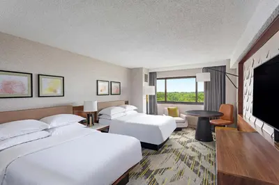 a hotel room with two beds and a flat screen tv at Sheraton Edison in Edison