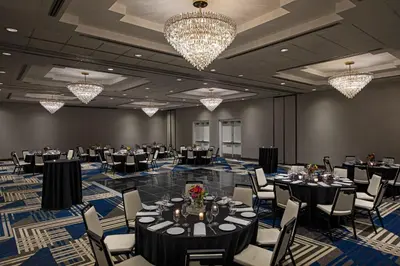 a banquet hall with tables and chairs and chandeliers at Sheraton Edison in Edison