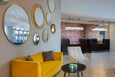 a lobby with a yellow couch and a table and mirrors at Sheraton Edison in Edison