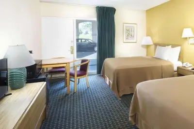 a hotel room with two beds and a desk at Howard Johnson by Wyndham Newburgh in Newburgh