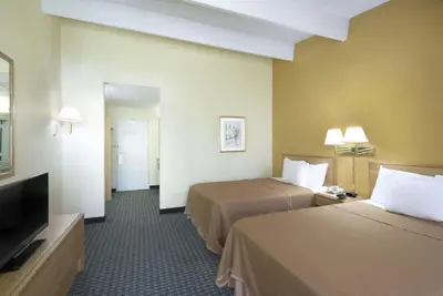 a hotel room with two beds and a flat screen tv at Howard Johnson by Wyndham Newburgh in Newburgh