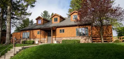 a large wooden house with a green lawn at Skytop Lodge in Skytop
