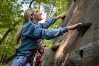 a woman climbing on a rock wall with a man at Skytop Lodge in Skytop