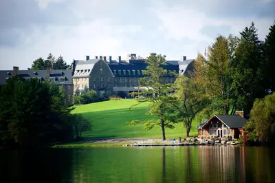 a large building with a house next to a lake at Skytop Lodge in Skytop