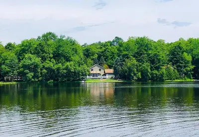 a house on the shore of a large lake at Mt. Maplewood Lake House in Blakeslee
