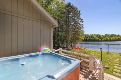 a hot tub on a deck next to a house at Mt. Maplewood Lake House in Blakeslee