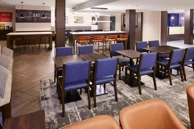 a restaurant with wooden tables and blue chairs at Hampton Inn Newark Airport in Newark