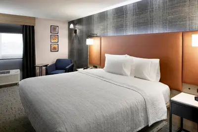 a hotel room with a large bed and a blue chair at Hampton Inn Newark Airport in Newark