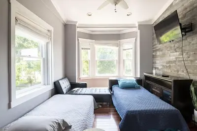 a room with two beds and a tv and two windows at Riverfront Penthouse Suite in Midtown Harrisburg near Hershey in Harrisburg