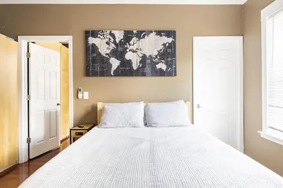 a bedroom with a white bed with a map on the wall at Riverfront Penthouse Suite in Midtown Harrisburg near Hershey in Harrisburg