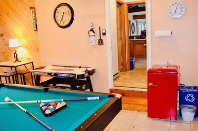 a room with a pool table and a clock on the wall at Mt. Maplewood Lake House Apt. in Blakeslee