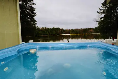 a large blue swimming pool with a view of a lake at Mt. Maplewood Lake House Apt. in Blakeslee