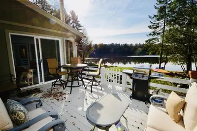 a patio with a table and chairs and a dog at Mt. Maplewood Lake House Apt. in Blakeslee