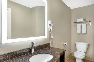 a bathroom with a sink and a toilet and a mirror at Best Western Fort Lee in Fort Lee
